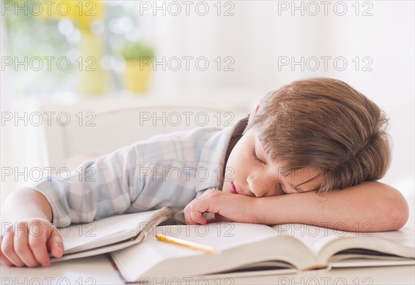 Boy (10-11 years) sleeping on books while doing homework. 
Photo : Daniel Grill