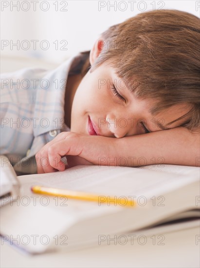 Boy (10-11 years) sleeping on books while doing homework. 
Photo : Daniel Grill