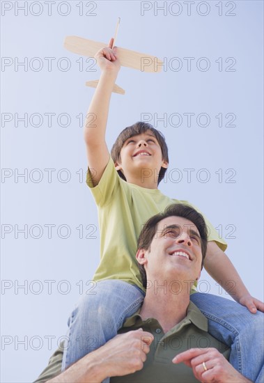 Father carrying son (10-11 years) on shoulders with model airplane. 
Photo : Daniel Grill