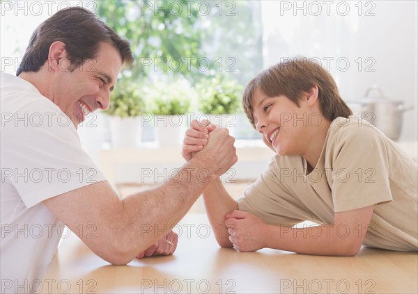 Father and son (10-11 years) arm wrestling. 
Photo : Daniel Grill