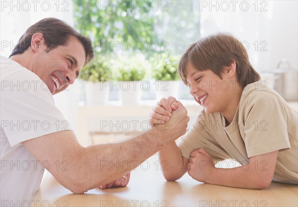 Father and son (10-11 years) arm wrestling. 
Photo : Daniel Grill