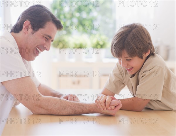 Father and son (10-11 years) arm wrestling. 
Photo : Daniel Grill