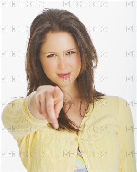 Portrait of smiling young woman pointing with finger, studio shot.
Photo: Daniel Grill