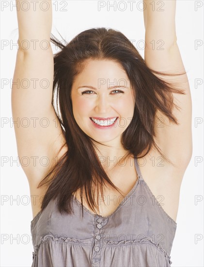 Portrait of smiling young woman with arms up, studio shot. 
Photo : Daniel Grill