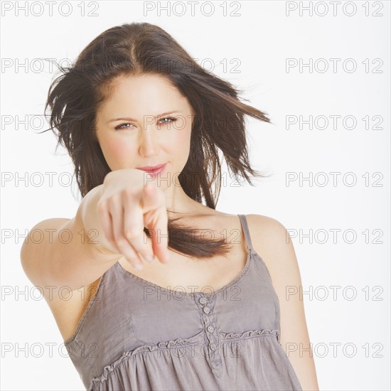 Portrait of young woman pointing with finger, studio shot. 
Photo : Daniel Grill