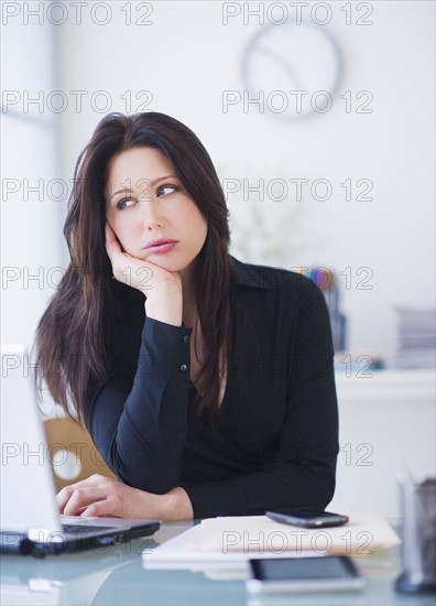 Businesswoman sitting at desk. 
Photo : Daniel Grill