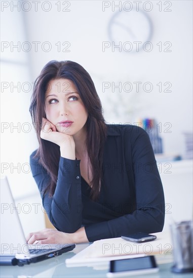 Businesswoman sitting at desk. 
Photo : Daniel Grill