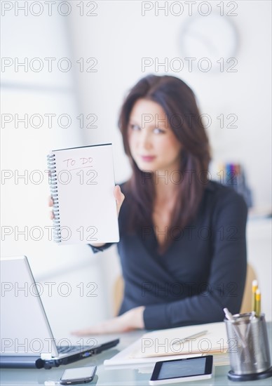 Businesswoman at desk showing to do list. 
Photo: Daniel Grill