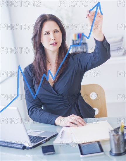 Businesswoman drawing graph. 
Photo : Daniel Grill