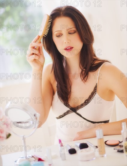 Young woman brushing hair. 
Photo : Daniel Grill