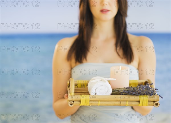 Young woman carrying tray with spa equipment, studio shot. 
Photo: Daniel Grill