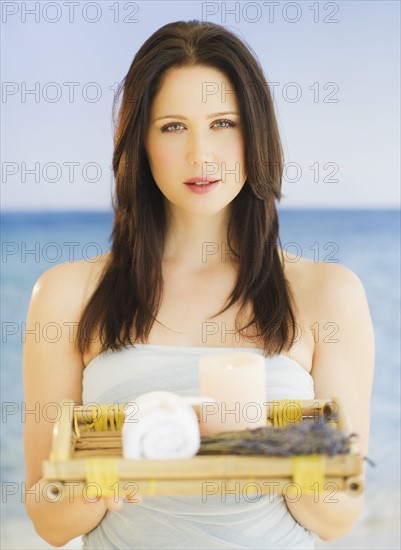 Young woman carrying tray with spa equipment, studio shot. 
Photo : Daniel Grill