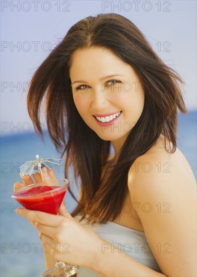 Portrait of young woman with cocktail, studio shot. 
Photo : Daniel Grill