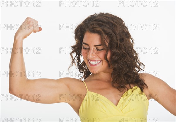 Portrait of young woman showing her biceps, studio shot. 
Photo : Daniel Grill