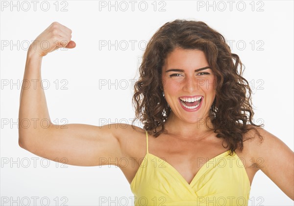 Portrait of young woman showing her biceps, studio shot. 
Photo : Daniel Grill