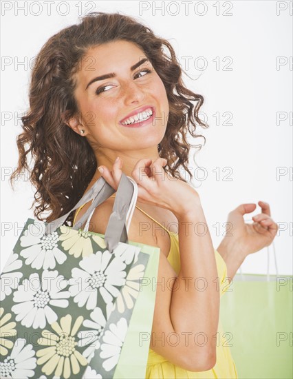 Portrait of smiling woman carrying shopping bags, studio shot. 
Photo : Daniel Grill