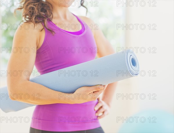 Woman holding rolled up yoga mat. 
Photo : Daniel Grill