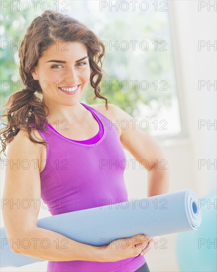 Woman holding rolled up yoga mat. 
Photo : Daniel Grill