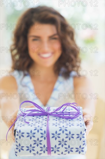 Smiling woman giving present. 
Photo : Daniel Grill