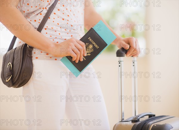 Close up of woman with luggage and passport. 
Photo : Daniel Grill