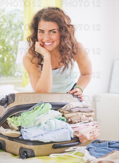 Smiling woman packing suitcase . 
Photo : Daniel Grill