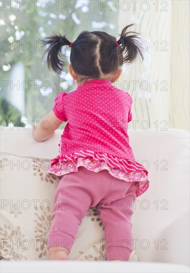 Baby girl (12-17 months) looking through window. 
Photo: Daniel Grill
