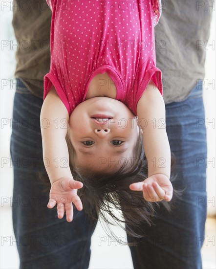 Father holding baby daughter (12-17 months) upside down. 
Photo: Daniel Grill