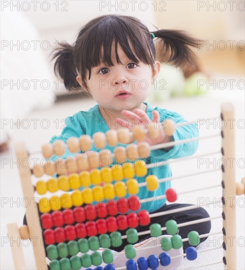 Portrait of baby girl (12-17 months) playing with abacus. 
Photo: Daniel Grill