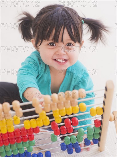 Portrait of baby girl (12-17 months) playing with abacus. 
Photo: Daniel Grill