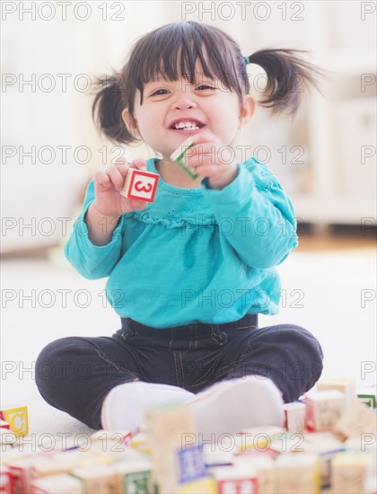 Portrait of baby girl (12-17 months) playing alphabet blocks. 
Photo : Daniel Grill