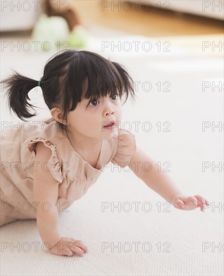 Portrait of baby girl (12-17 months) crawling on carpet. 
Photo: Daniel Grill