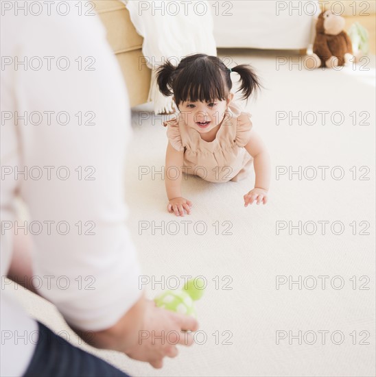 Father encouraging baby daughter (12-17 months) to crawl. 
Photo : Daniel Grill