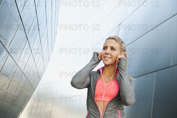 USA, California, Los Angeles, Young woman listening to music on headphones while training.