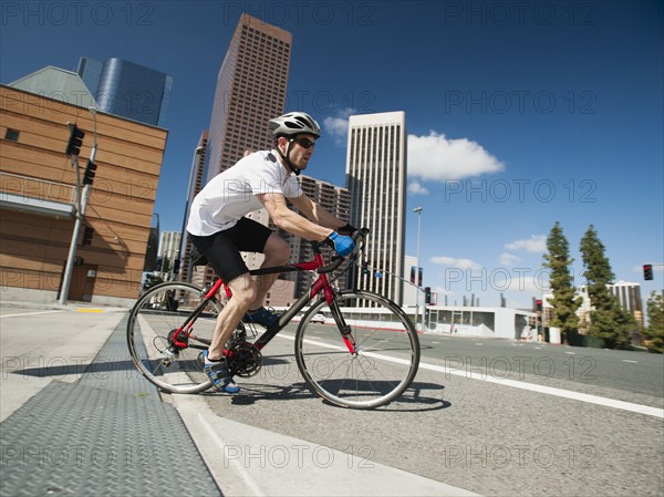 USA, California, Los Angeles, Young man road cycling on city street.