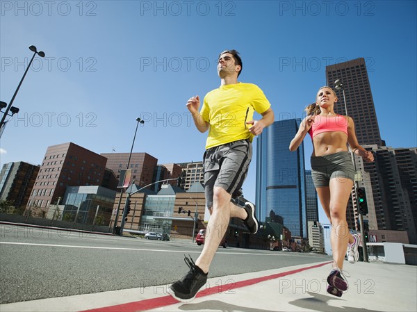 USA, California, Los Angeles, Young man and young woman running on city street.