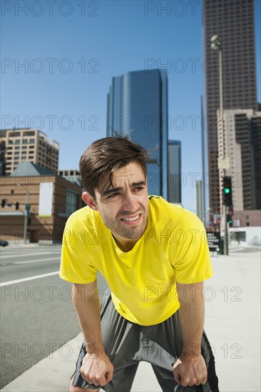 USA, California, Los Angeles, Young man resting after running on city street.