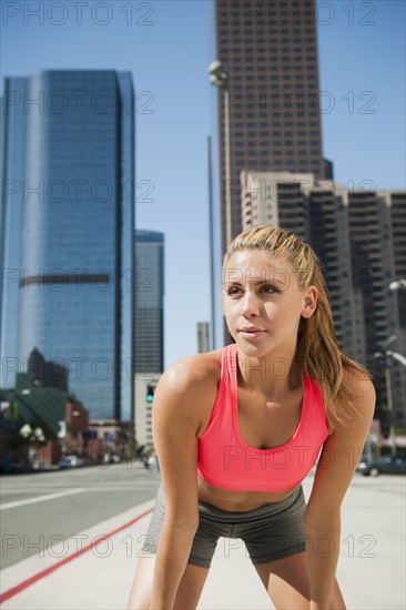 USA, California, Los Angeles, Young woman resting after running on city street.