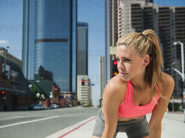 USA, California, Los Angeles, Young woman resting after running on city street.