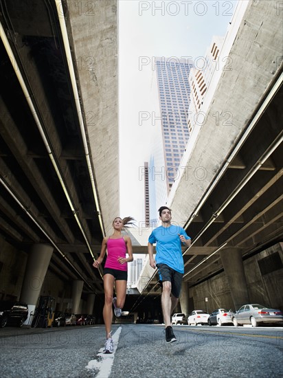 USA, California, Los Angeles, Young man and young woman running on city street.