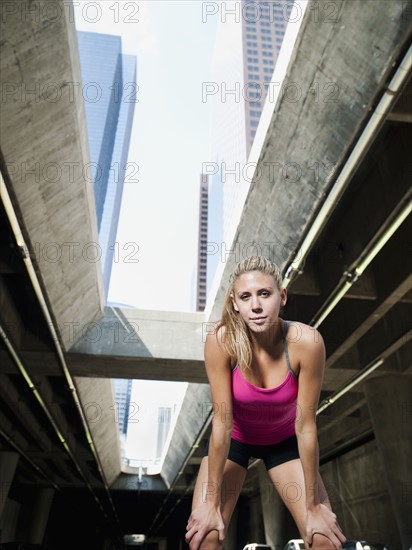 USA, California, Los Angeles, Young woman resting after running on city street.