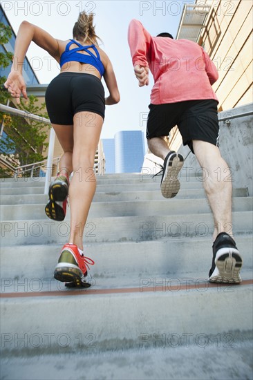 USA, California, Los Angeles, Young man and young woman running on city street.