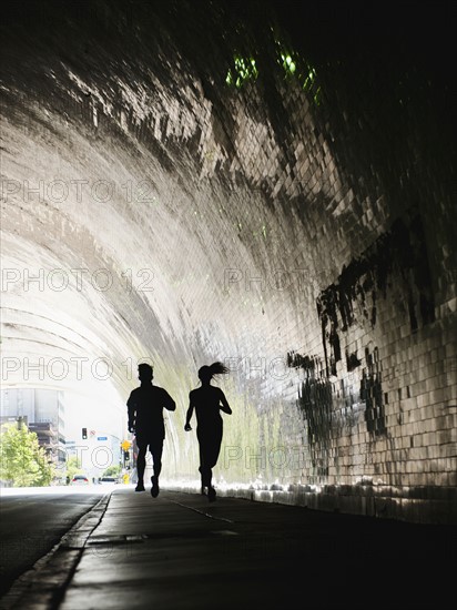 USA, California, Los Angeles, Man and woman running in tunnel.