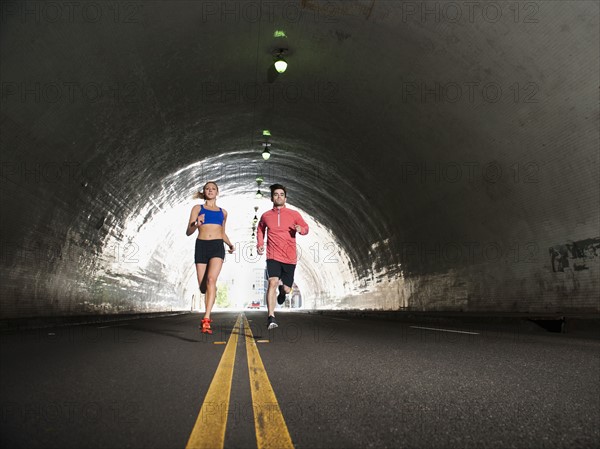 USA, California, Los Angeles, Young man and young woman running in tunnel.