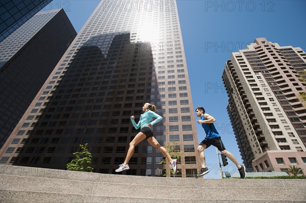 USA, California, Los Angeles, Young man and young woman running in city.