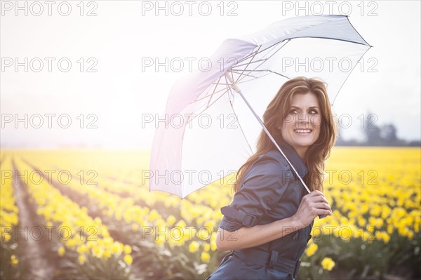 USA, Washington, Skagit Valley, Woman with umbrella against daffodil field. 
Photo : Take A Pix Media