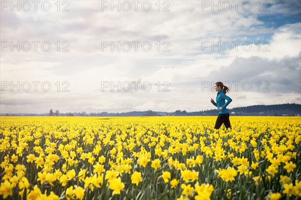 USA, Washington, Skagit Valley, Woman running through daffodil field. 
Photo: Take A Pix Media