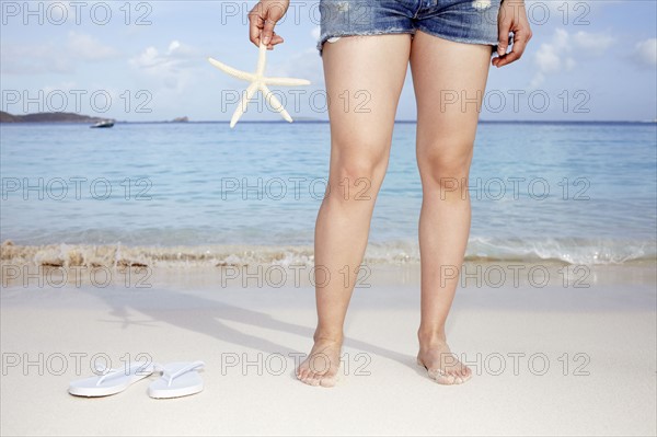 United States Virgin Islands, St. John, Woman on bench holding starfish. 
Photo : Winslow Productions