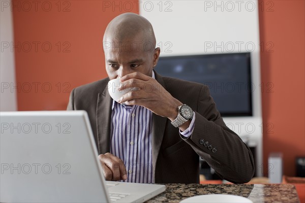 Man enjoying coffee while using laptop. 
Photo : Dan Bannister