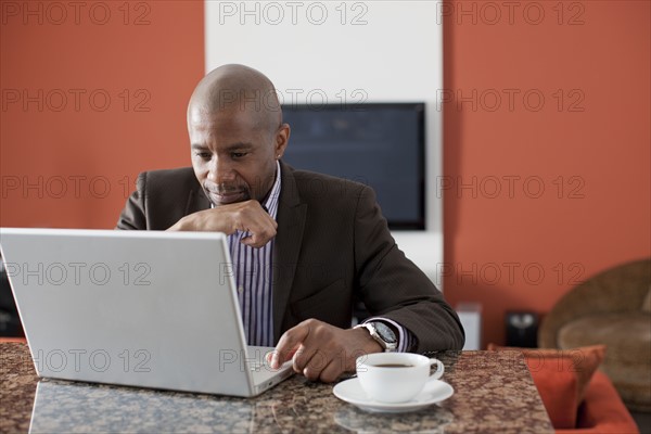 Man enjoying coffee while using laptop. 
Photo : Dan Bannister