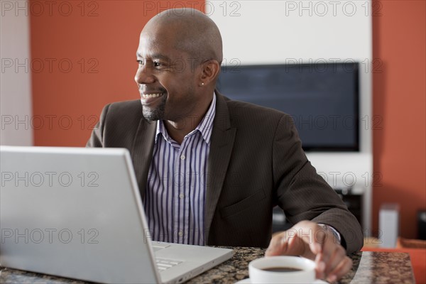 Man enjoying coffee while using laptop. 
Photo : Dan Bannister